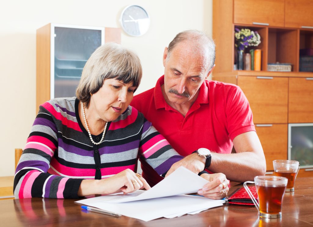 Elderly couple reviewing Health and Welfare LPA paperwork with advisor at home in Norfolk.